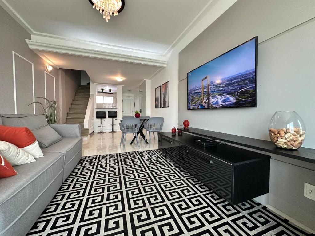Duplex Por do Sol a Beira Mar في فلوريانوبوليس: غرفة معيشة مع أريكة وتلفزيون بشاشة مسطحة