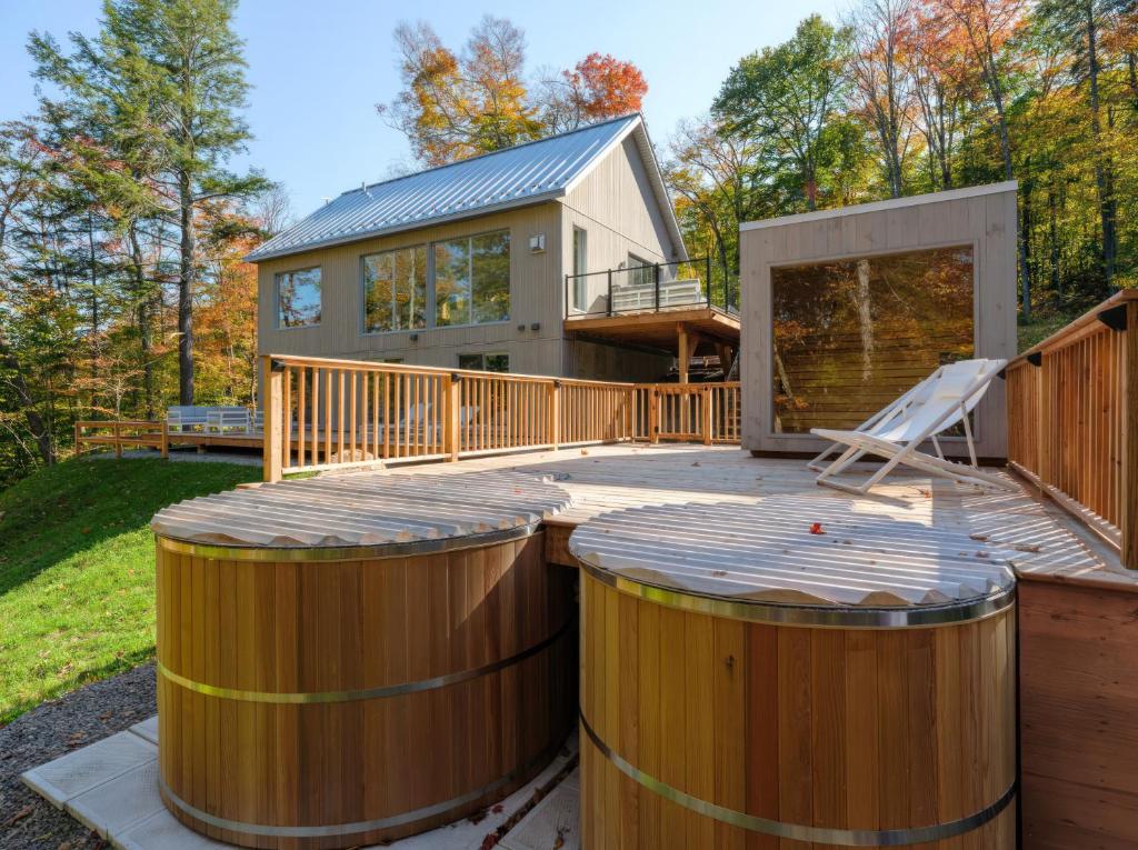 a house with two wooden barrels on a deck at Maison Solus - Mont Tremblant in Lac-Superieur