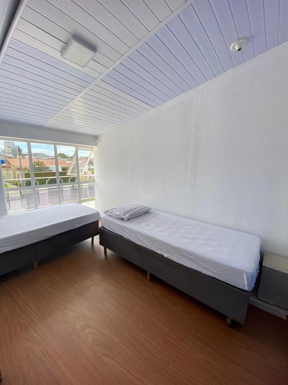 a room with two beds and a window in it at Quarto Duplo Casal Jd Botânico in Curitiba