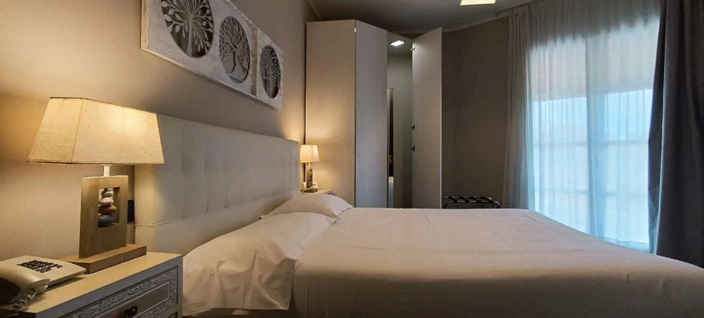 Hotel Palladium في Monastir: غرفة نوم بسرير ابيض كبير وهاتف