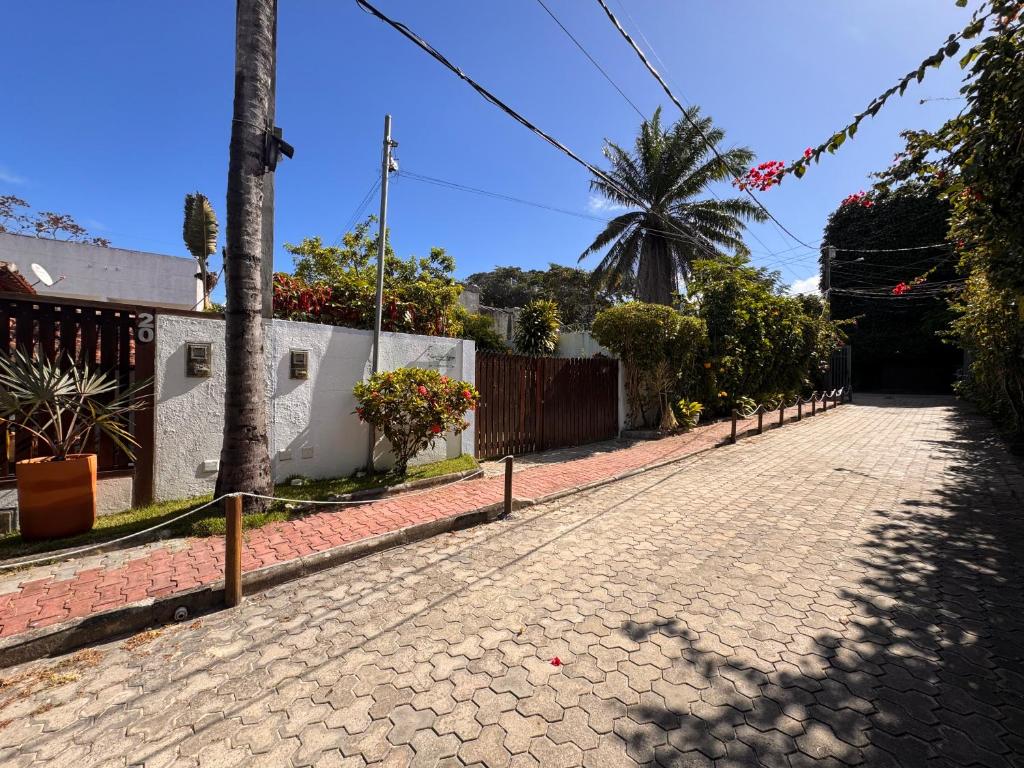 una strada di ciottoli con una recinzione e una palma di Casa Vila Tortuga a Arraial d'Ajuda