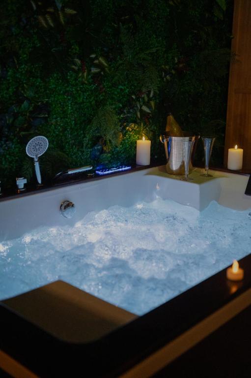 a bath tub with two candles and two lit candles at Loft avec Spa Privatif in Frameries