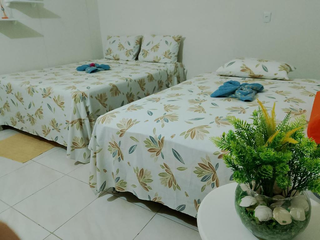 a bedroom with two beds and a table with plants at hospedaria Cantinho da Rosa in Santo Amaro