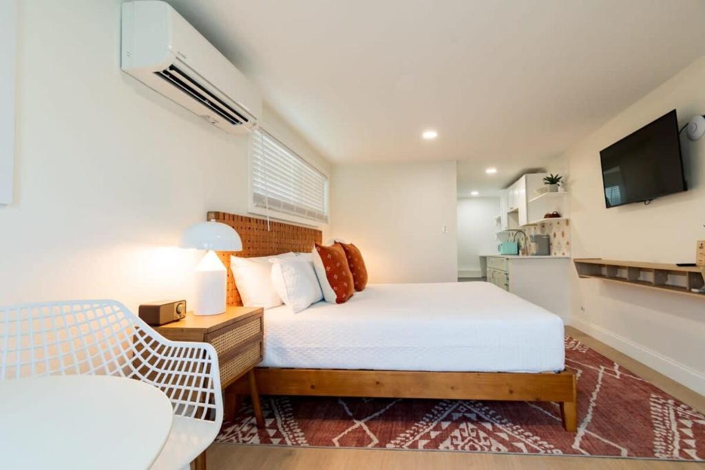 a bedroom with a bed and a chair and a television at THE JUNI Studio Surf Paradise in Heart of Cocoa Beach in Cocoa Beach