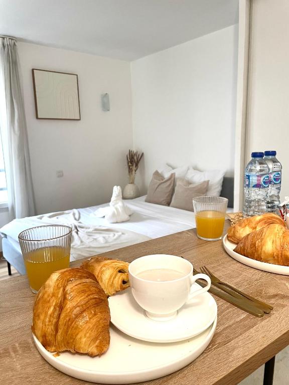 ein Tisch mit einem Teller Croissants und einer Tasse Kaffee in der Unterkunft Le Michel Ange in Courbevoie