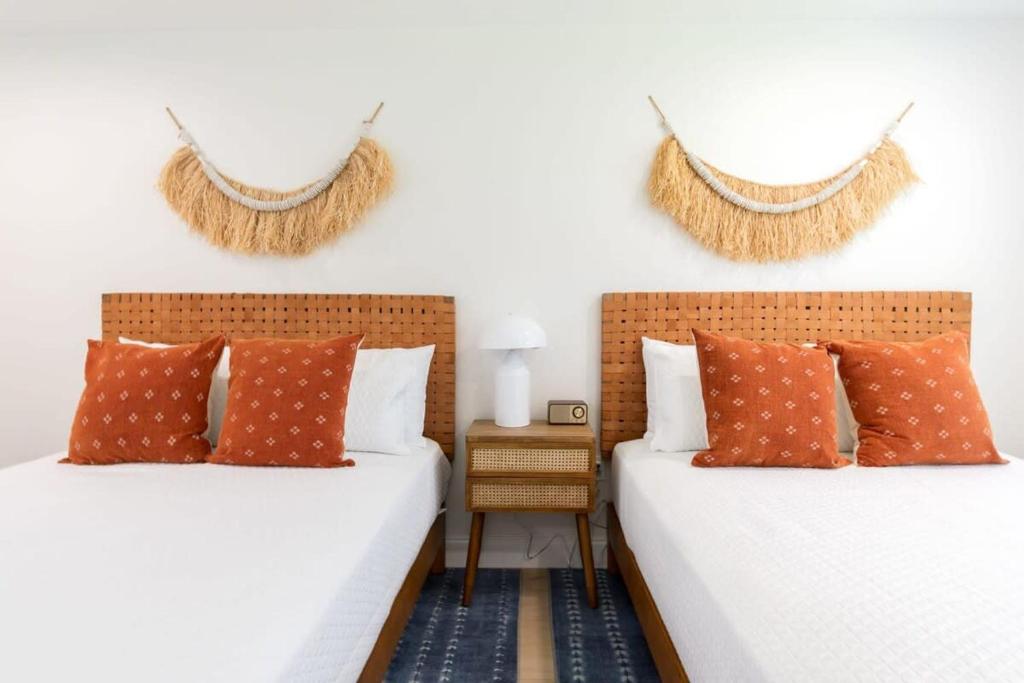 2 camas con almohadas de color naranja en un dormitorio en THE JUNI Stunning Studio Walk to Everything, en Cocoa Beach