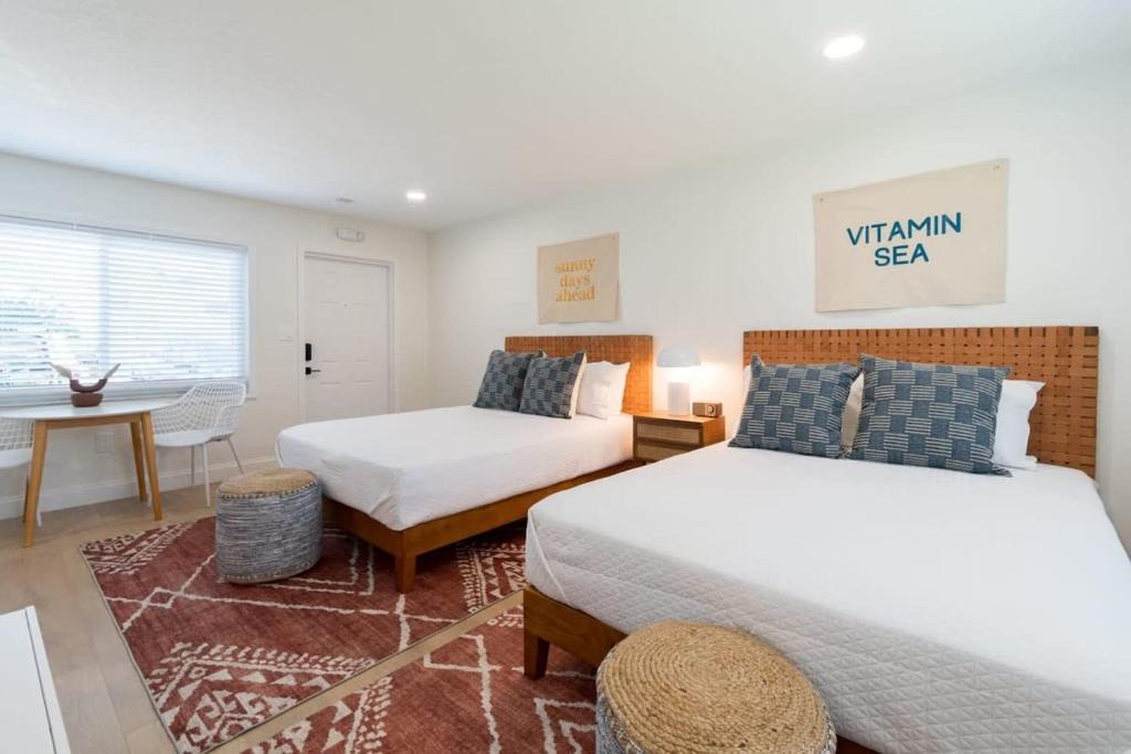 a bedroom with two beds and a table and a desk at THE JUNI - Studio Steps to Beach Downtown Cocoa in Cocoa Beach