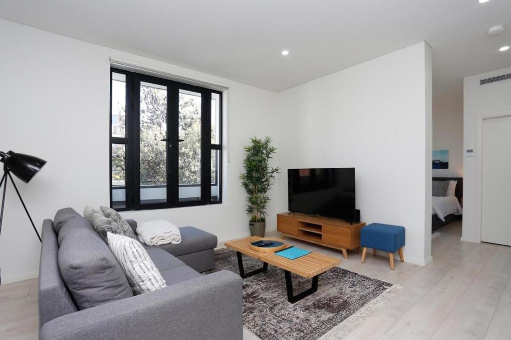 a living room with a couch and a tv at Hoffy's Place - Modern one bedroom with AC in Sydney