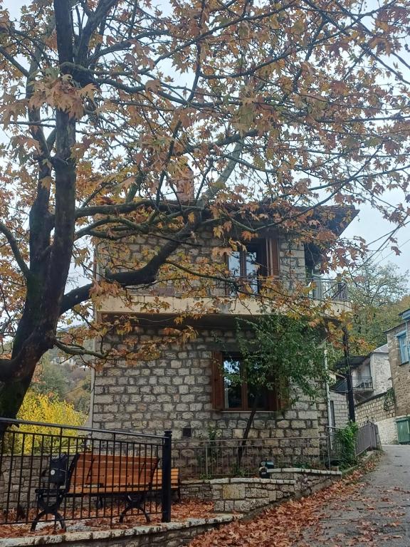 una casa di pietra con un albero di fronte di Gouvas stone house a Karpenision