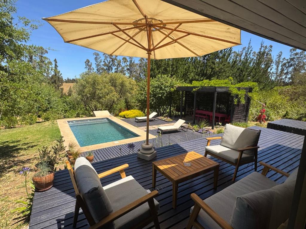 una terrazza in legno con ombrellone e piscina di Casa Lodge Campo La Tranquilidad a El Convento