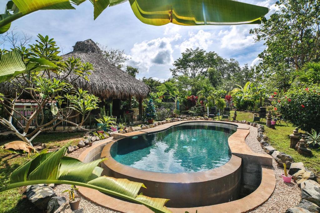 una piscina in un giardino con tetto di paglia di Glamping Hotel Flor y Bambu a Playa Grande