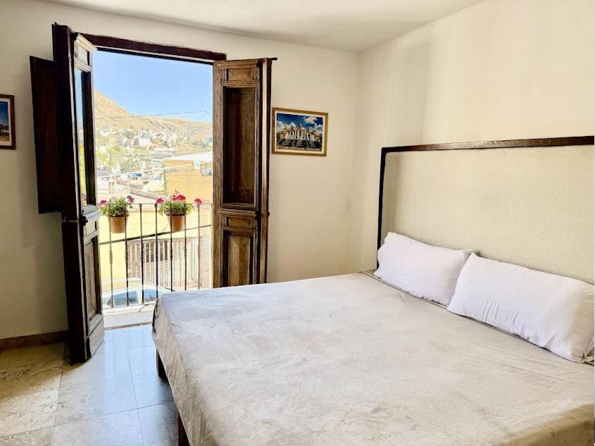 Santuario 71 Lofts and apartments في غواناخواتو: غرفة نوم بها سرير ونافذة كبيرة