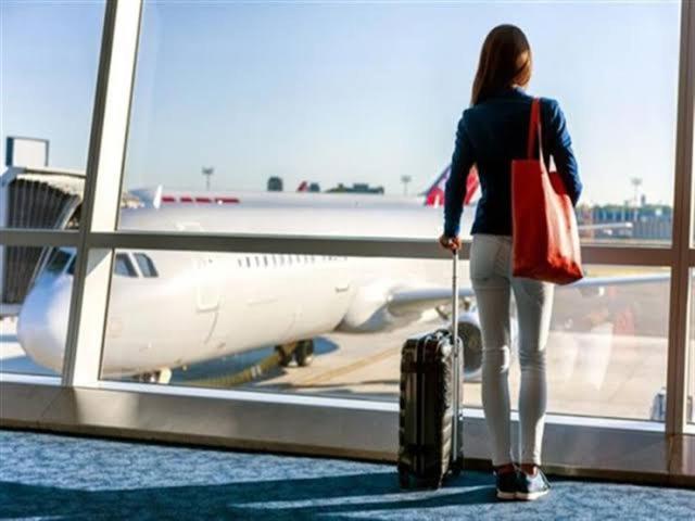 a woman standing with a suitcase looking at an airplane at Le Shot tours Hotel in Al Jafr