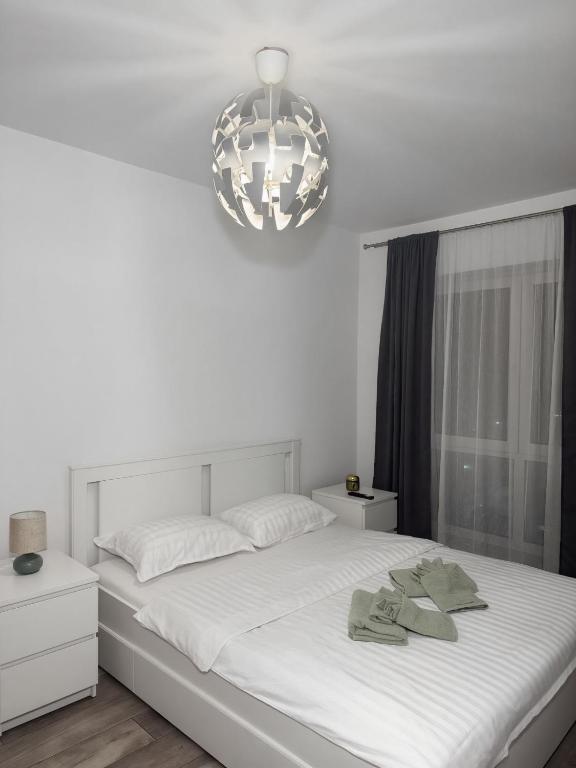 a bedroom with a large white bed with a chandelier at Luxury Avantgarden apartament in Braşov