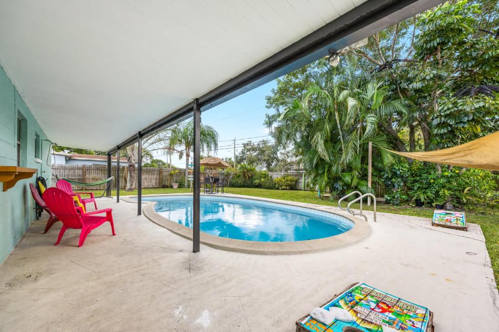 a swimming pool in a yard with a red chair at Island Escape w Private Pool & Outdoor Haven in Merritt Island