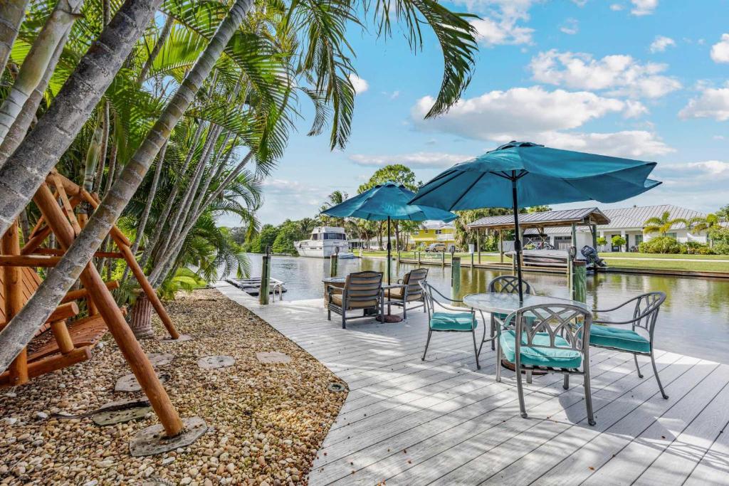 a wooden deck with chairs and tables and umbrellas at 4BR 2-5BA Waterfront Oasis w Pool and Dock in Cocoa Beach