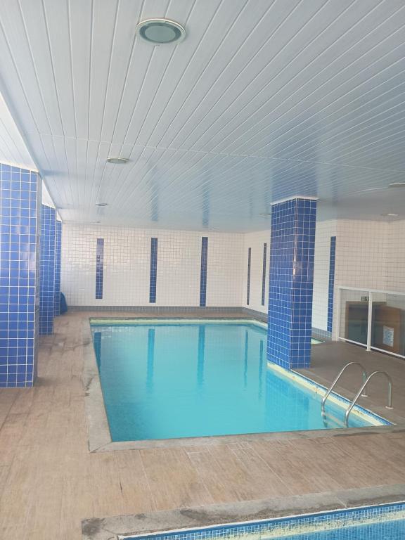 a large swimming pool with blue tiles in a building at Apto Pe na areia # Piscina e Churrasqueira in Mongaguá