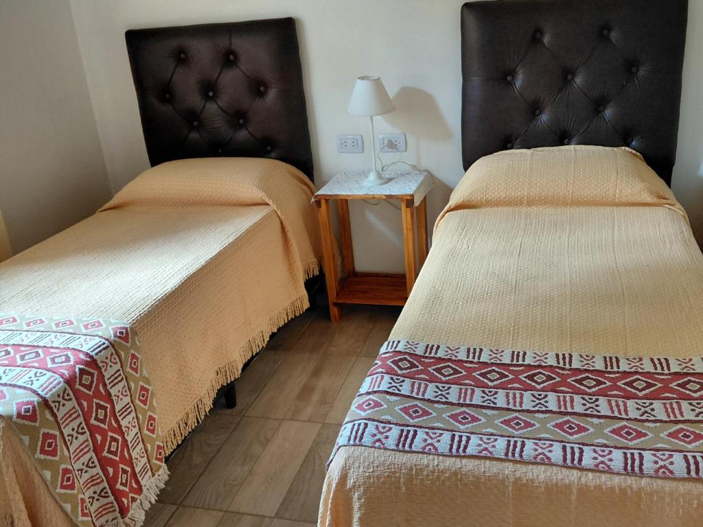 ein Hotelzimmer mit zwei Betten und einem Tisch in der Unterkunft Cabañas Río in Huerta Grande