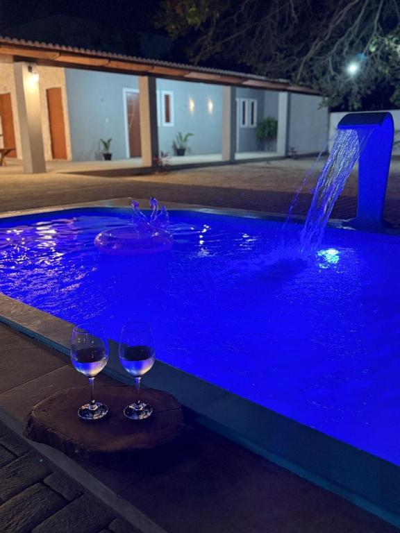 due bicchieri di vino seduti accanto a una piscina con una fontana di Rancho da Serra a Lagoa Nova