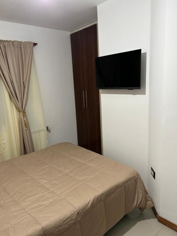 维拉卡洛斯帕兹Dpto Carlos Paz的卧室里有一张床，墙上有一台电视