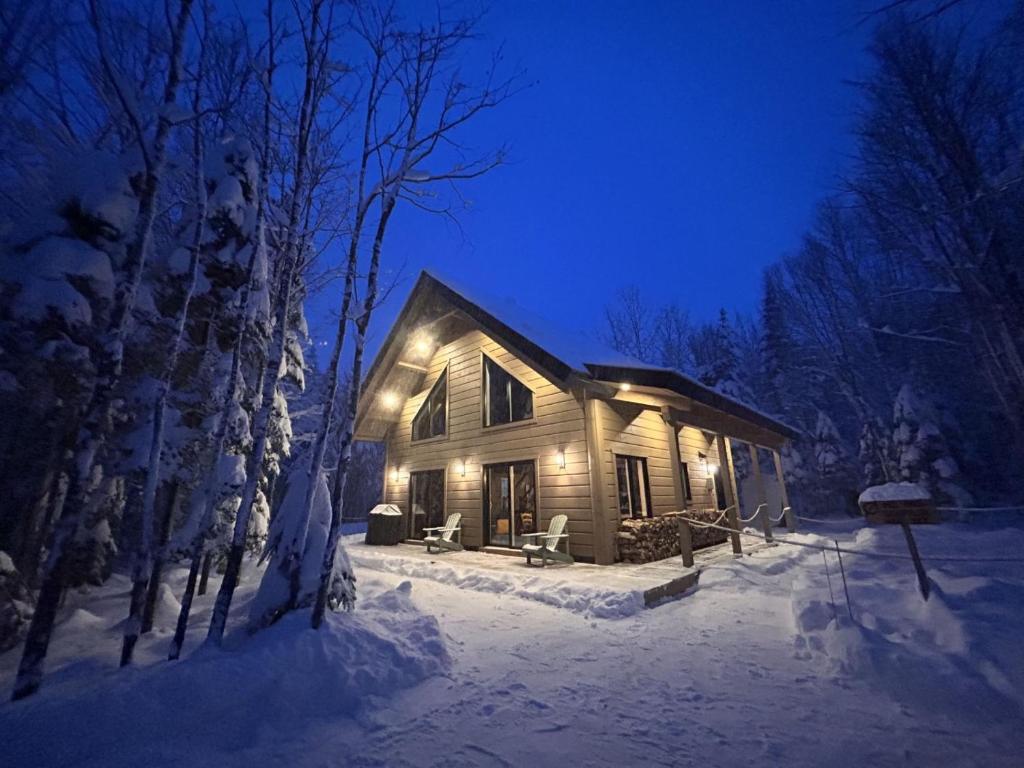 a cabin in the snow at night with lights at Repaire des bouleaux in Saint-Tite-des-Caps