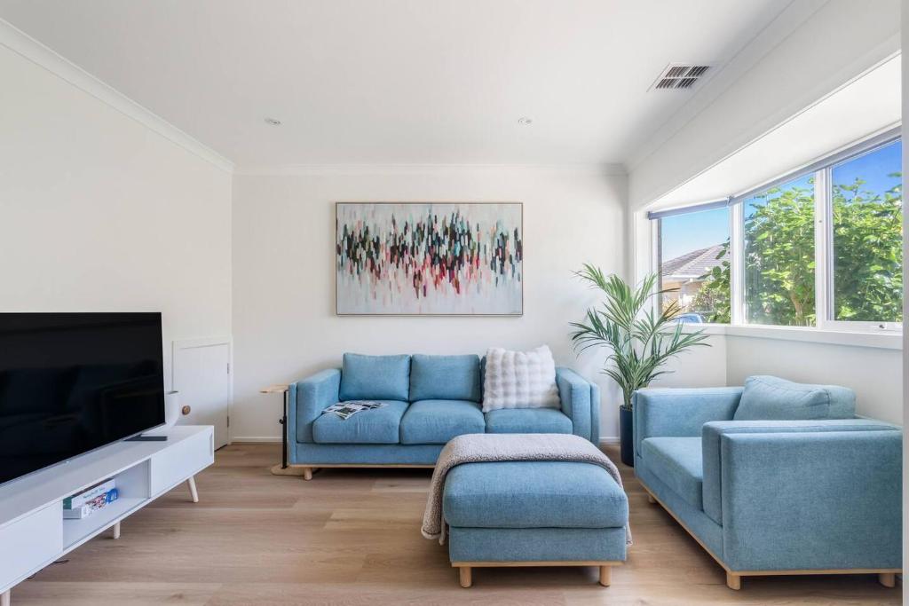 een woonkamer met een blauwe bank en een tv bij Foreshore Escape - Beachside Comfort near Dining in Safety Beach