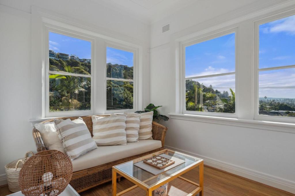 a living room with a couch and three windows at Blu Ocean Views Collaroy - Sunroom & BBQ in Collaroy