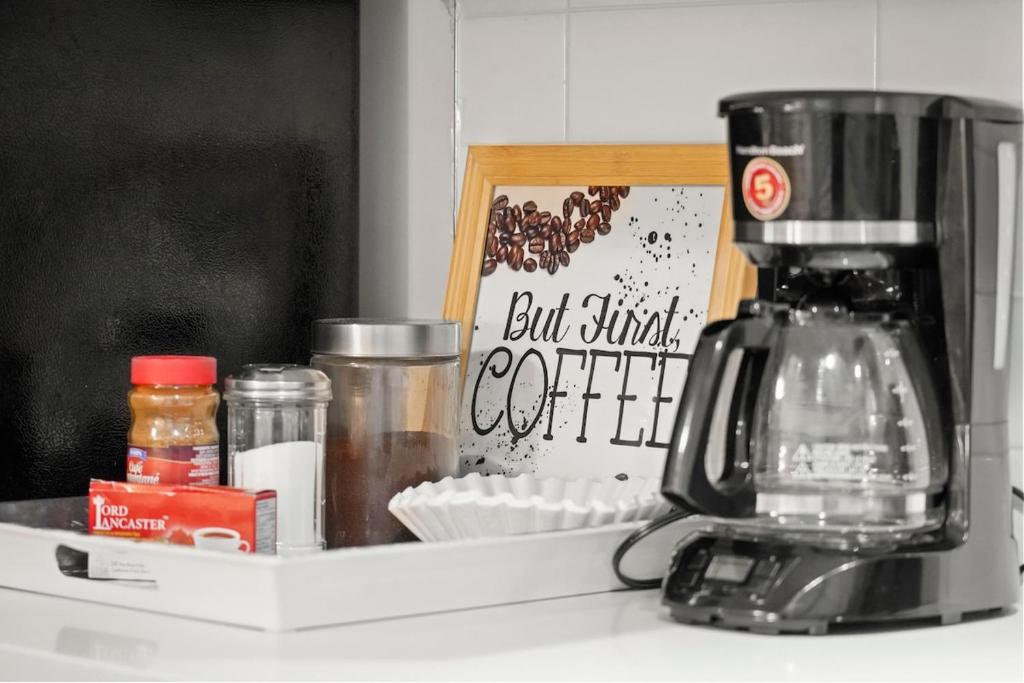 2 bed Suburban Oasis in Surrey في سوري: كاونتر المطبخ مع آلة صنع القهوة والمكونات الأخرى