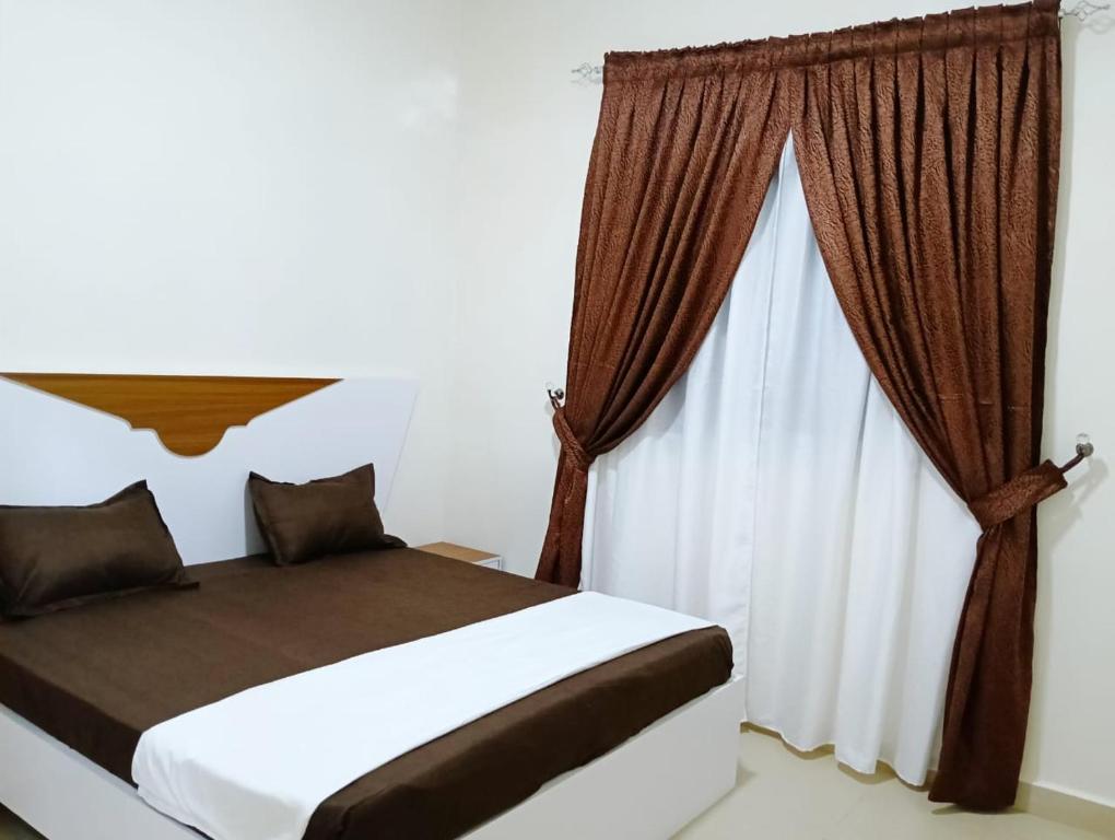 ein Schlafzimmer mit einem Bett und einem Fenster mit Vorhängen in der Unterkunft Royal Comfort Lodge in Thiès