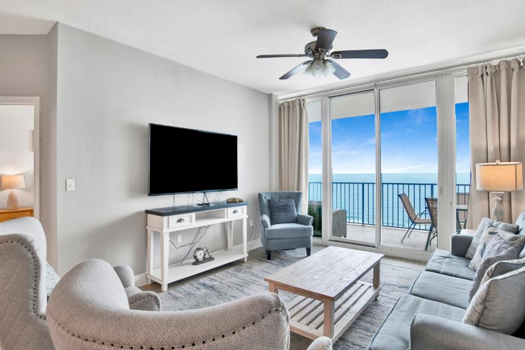 a living room with a tv and a couch and chairs at Lighthouse 1713 in Gulf Shores