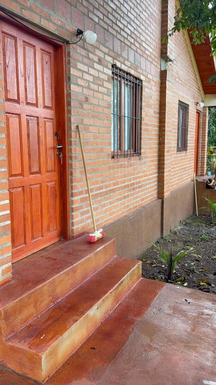 a red door of a brick building with a broom at Cabañas la flor in Puerto Piray