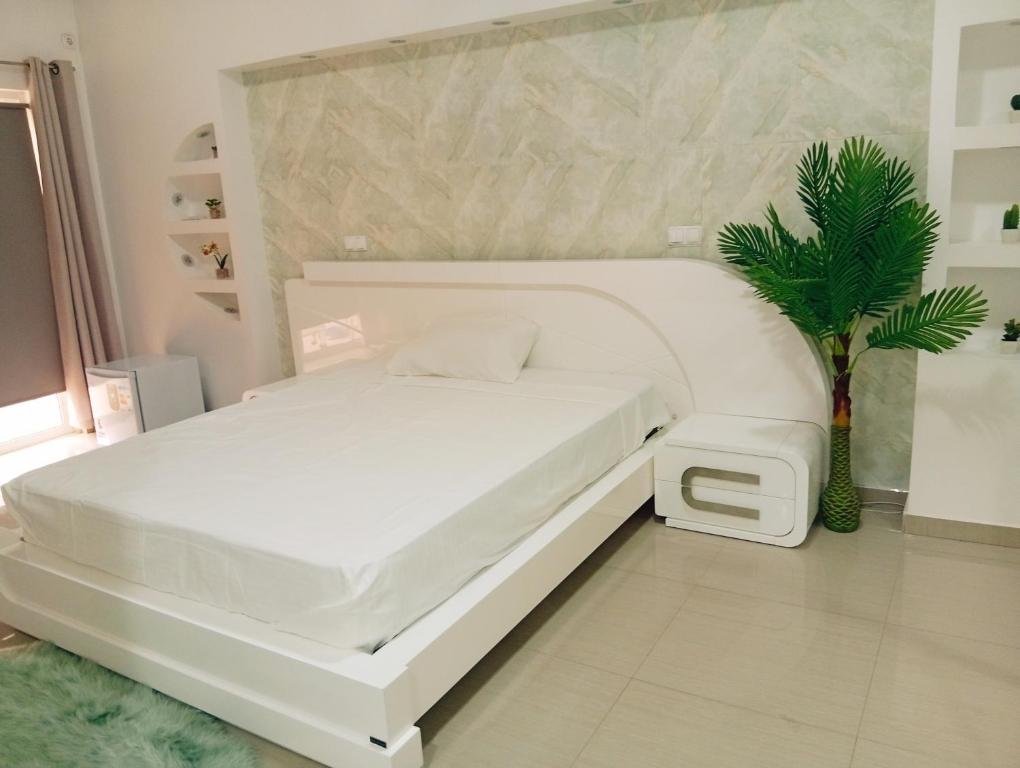 普拉亚Four Palms Boutique Hotel的一间种植了盆栽植物的房间里一张白色的床