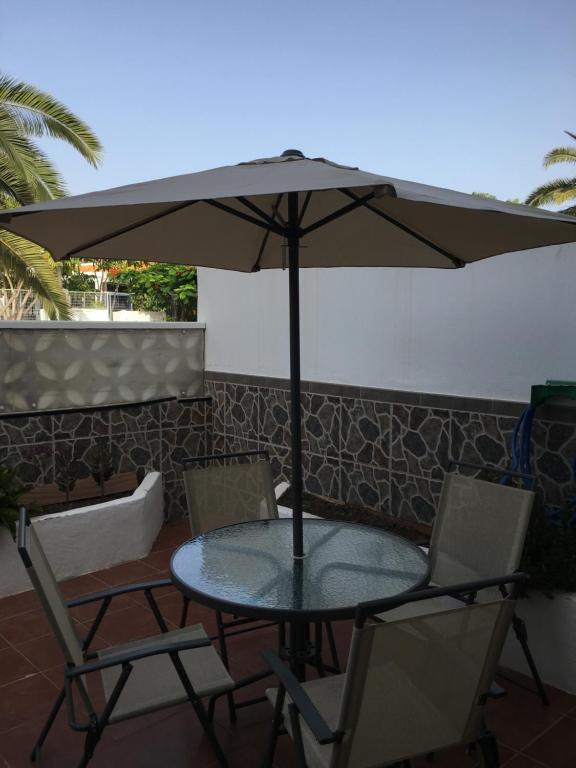 una mesa y sillas bajo una sombrilla en un patio en La Palmita de Canarias en Agaete