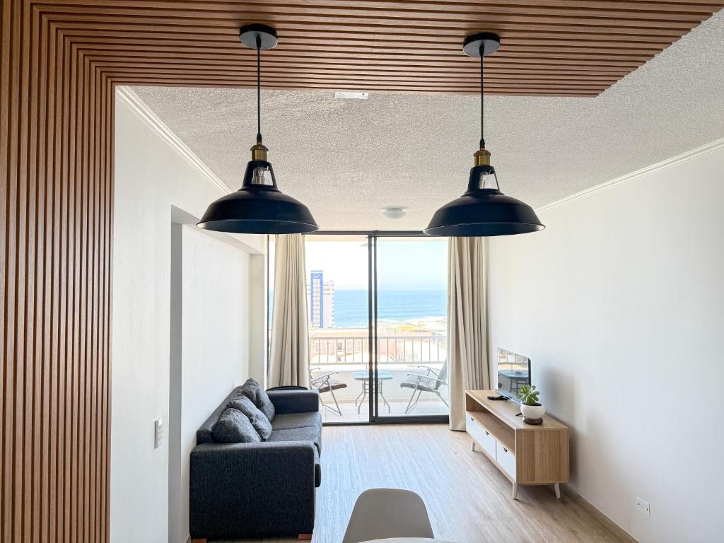 a living room with two pendant lights and a couch at Departamento cerca de Cavancha Estacionamiento incluido in Iquique