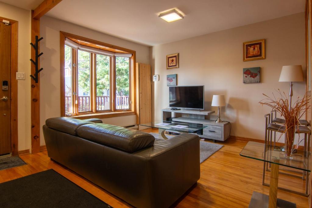 a living room with a leather couch and a television at Cozy bungalow near Montreal and shops in Longueuil