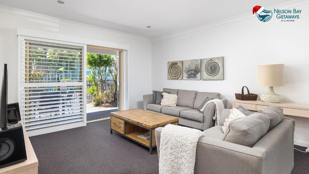 Una sala de estar con dos sofás y un televisor. en Oaks Pacific Blue Pool spa more in complex, en Salamander Bay