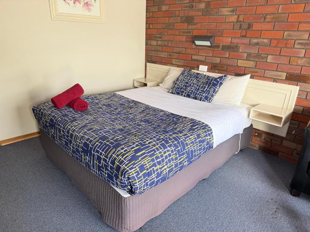a bedroom with a bed with a brick wall at Coorrabin Motor Inn in Stawell