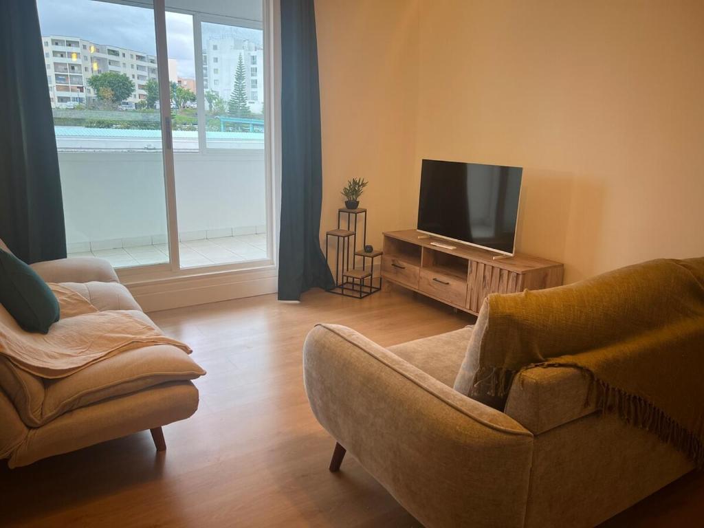 圣玛丽La Varangue Bleue T3 bright near airport的客厅配有2把椅子和平面电视