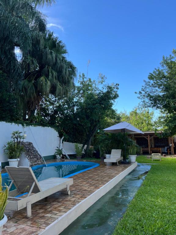 einen Hinterhof mit einem Pool mit Stühlen und einem Sonnenschirm in der Unterkunft Casa de huéspedes in Puerto Iguazú