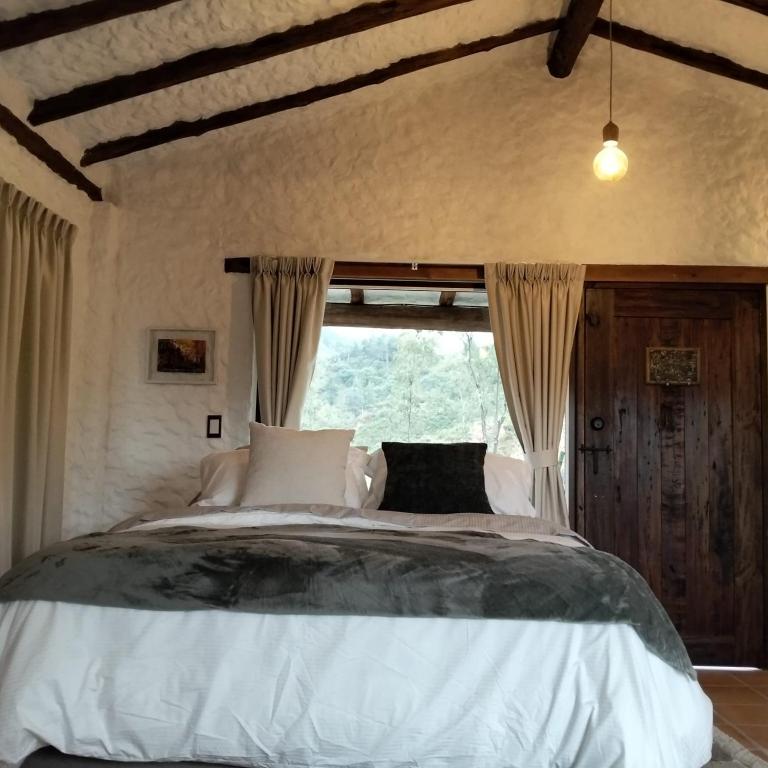 a bedroom with a large bed with a window at Posada Iglesia Vieja in Soatá