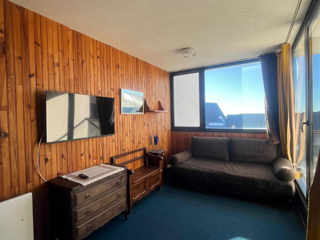 a room with a couch and a tv and a window at Appartement 4 Pers au Cœur de Super Besse - FR-1-814-142 in Super Besse