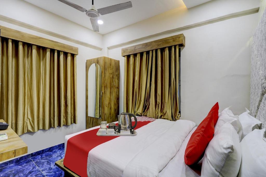 ein Schlafzimmer mit einem weißen Bett mit roten Kissen in der Unterkunft Hotel O Bhavy in Ahmedabad