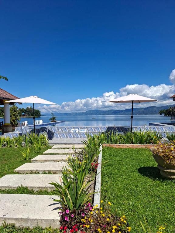 图克图克Juma cottages的院子里的小路，路旁摆放着遮阳伞和鲜花。