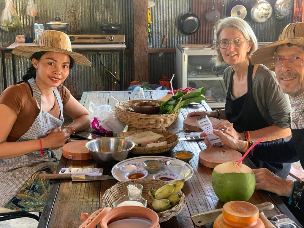 eine Gruppe von Menschen steht mit Essen um einen Tisch herum in der Unterkunft Battambang Eco Stay &cooking class in Battambang