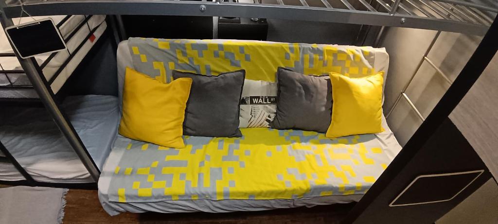 Chambre Privée Familiale 13m2 dans F2 partagé 30m2 في لو كرملين-بيستر: سرير مع وسائد صفراء ورمادية على رف