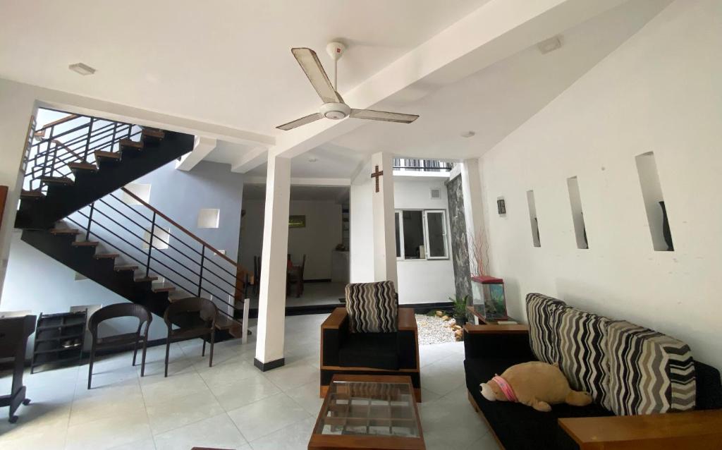 ein Wohnzimmer mit einem Deckenventilator und einer Treppe in der Unterkunft Hagiazo Guest Inn Mirissa in Telangapata