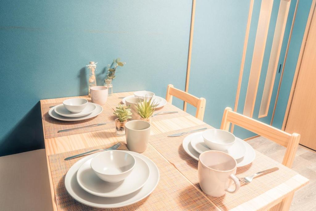a wooden table with white plates and cups on it at HMV Horyuji in Ikaruga