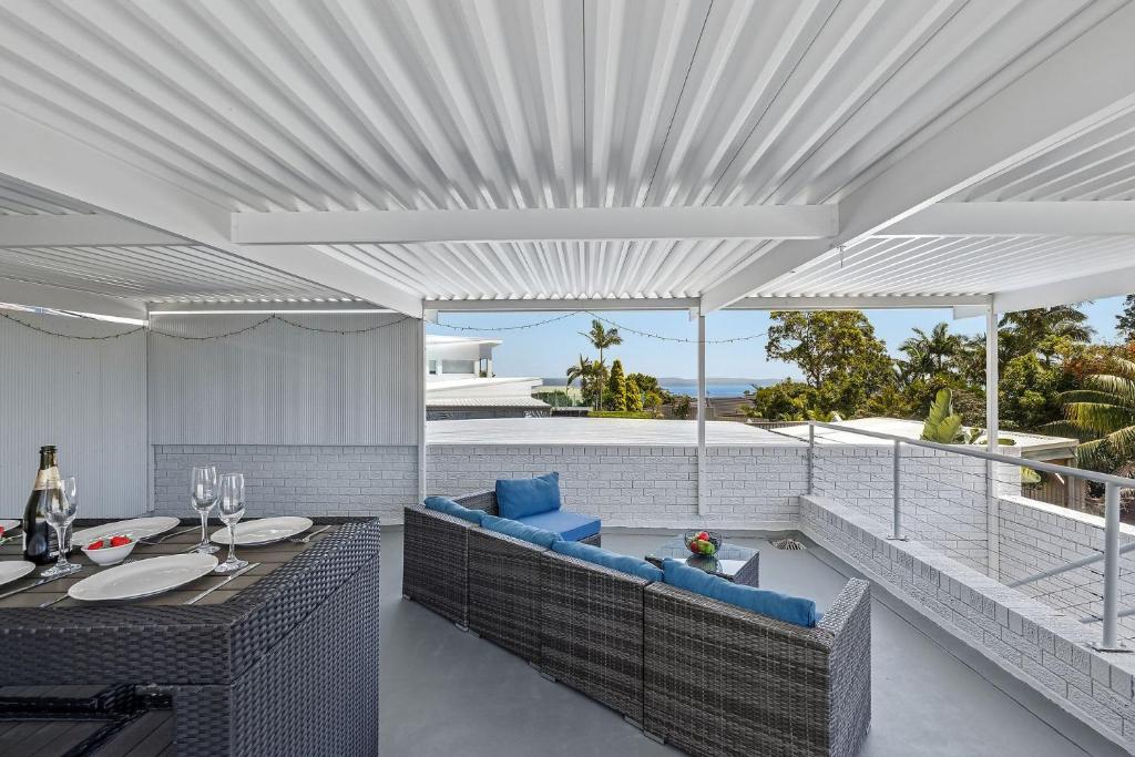 an outdoor patio with blue chairs and a table at Galoola Hidden Gem - 2,97 Galoola Drive, Rooftop outdoor area with spectacular views, Wi-Fi and air conditioning. in Nelson Bay