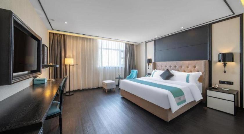 um quarto de hotel com uma cama grande e uma TV de tela plana em Xana Hotelle Jinan Daminghu North Gate em Jinan