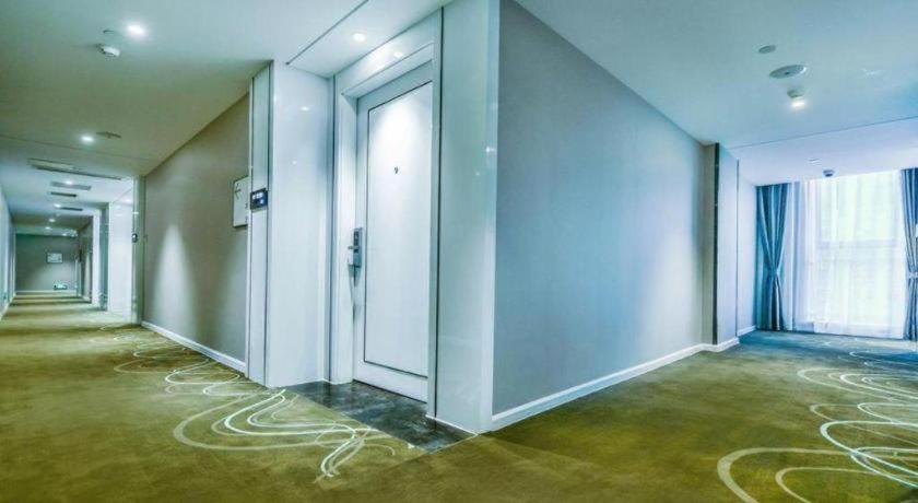 an empty room with a hallway with glass doors at Xana Hotelle Neijiang City Center Branch in Neijiang